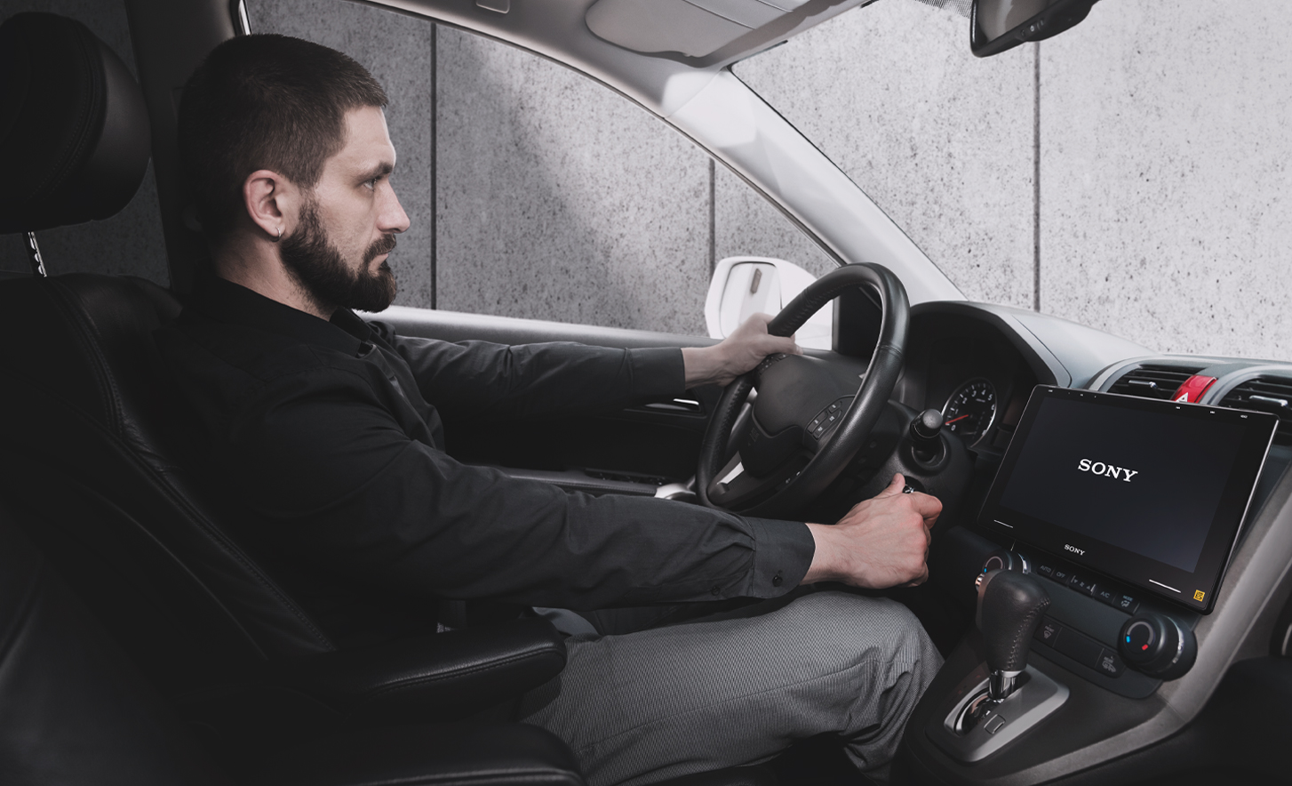 Slika osebe, ki obrača ključ za kontakt, z XAV-9550ES na armaturni plošči in logotipom Sony na zaslonu